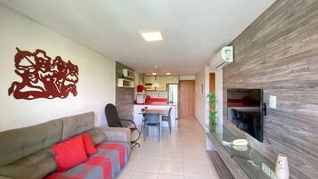 A modern living room with a sofa, a dining area, and a kitchen in the background.