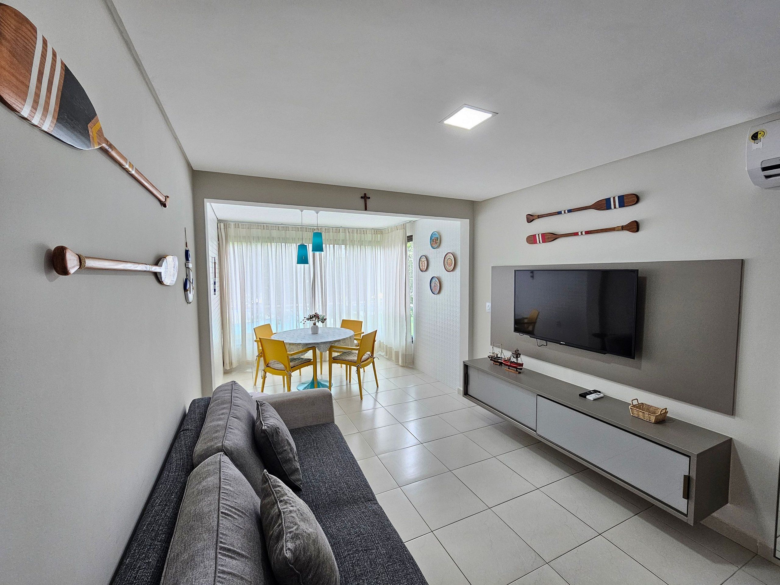 A modern living room with a sofa, TV, and dining area.