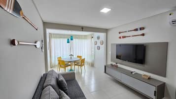 A modern living room with a sofa, TV, and dining area.