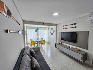 Ein modernes Wohnzimmer mit einer Couch, Fernseher und Essbereich.