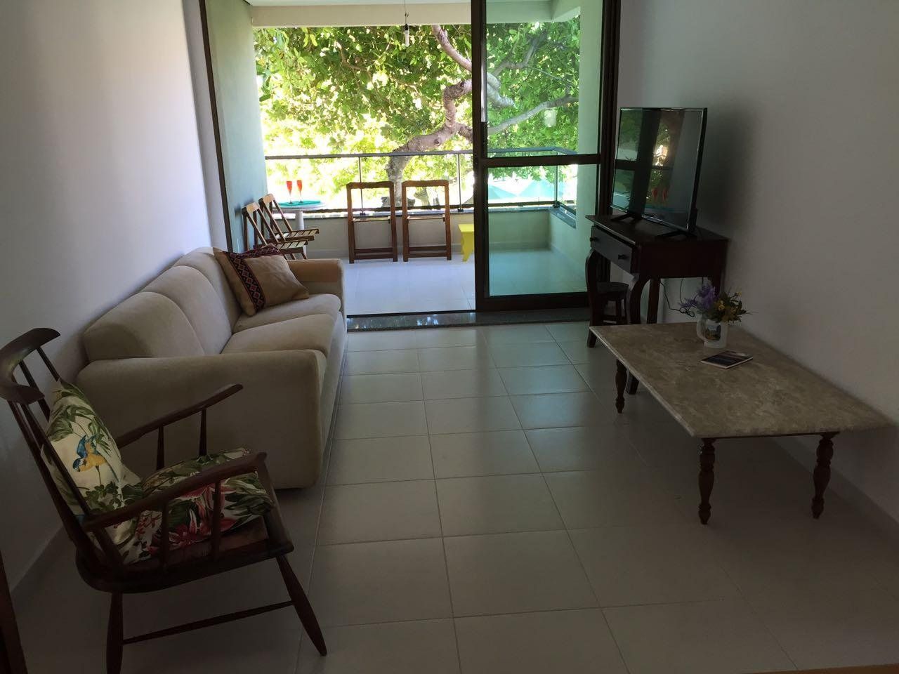 A living room with a sofa, a wooden chair, a coffee table, and a television.