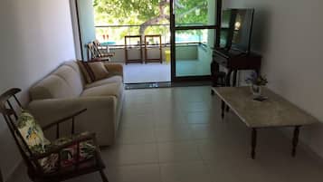 A living room with a sofa, a wooden chair, a coffee table, and a television.