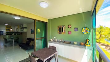 A dining area with a table and chairs, a kitchen with cabinets, a sliding glass door, and decorative wall art.