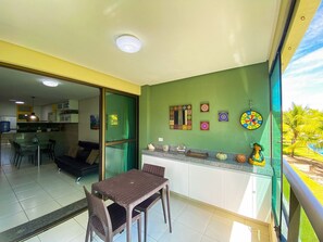 Uma sala de jantar com mesa e cadeiras, uma cozinha com armários, uma porta de vidro deslizante e arte decorativa nas paredes.