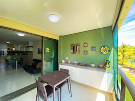 A dining area with a table and chairs, a kitchen with cabinets, a sliding glass door, and decorative wall art.