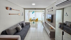 A modern living room with a sofa, TV, and decorative items. - Carneiros Beach Resort - Praia Carneiros (Tamandaré)