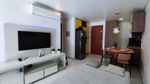 Uma cozinha moderna com geladeira embutida, uma mesa de jantar com cadeiras e uma TV de tela plana fixada na parede.