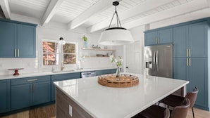 Une cuisine moderne avec des armoires de couleur turquoise, un grand îlot central et un réfrigérateur en acier inoxydable.