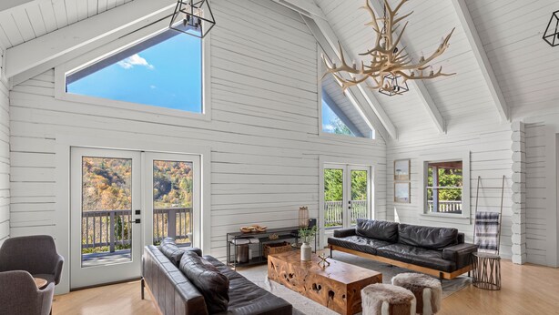 Un salon spacieux avec un plafond haut, de grandes fenêtres et un plafond en bois.