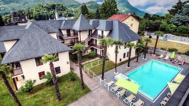 A hotel with multiple buildings, a swimming pool, and a mountainous backdrop. - Appartement de L'isard Bleu, Dans Résidence de Tourisme 3 Étoiles (Lourdes)