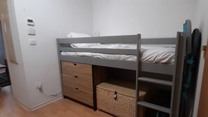 A bunk bed with a lower drawer and a shelf, a small stool, and a basket on the floor. - Appartement de L'isard Bleu, Dans Résidence de Tourisme 3 Étoiles (Lourdes)
