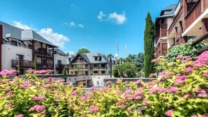 A row of multi-story buildings with balconies, surrounded by lush greenery and flowering plants. - Appartement de L'isard Bleu, Dans Résidence de Tourisme 3 Étoiles (Lourdes)