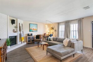 Ein Wohnzimmer mit Kamin, einer Couch, einem Couchtisch und einer Lampe.
