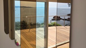 A view through a uniquely shaped window with a wooden deck and a scenic ocean view. - Authentic waterfront villa (1st line) with private beach access (Saint Raphael)