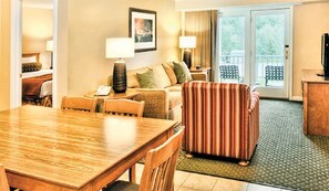 Relax in this inviting room with a dining table, armchair, sofa, and balcony access.
