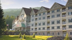 Un hotel de varios pisos con una fachada simétrica, balcones y un zócalo de piedra.