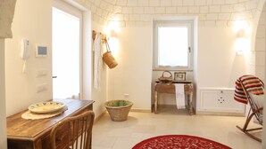 A cozy room with a brick ceiling, a wooden dining table, a large bowl, a rocking chair, and a red rug.