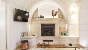 A cozy room with a fireplace, a television mounted above it, and a rustic wooden table.
