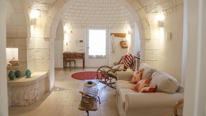 A cozy living room with a stone archway, a sofa, a coffee table, and a red rug.