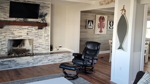 Una sala moderna con chimenea de piedra, sillón de cuero reclinable y televisor de pantalla plana montado en la pared.