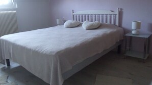 En pænt redt seng med puder, en sengetavlelampe og en hjerteformet dekoration på væggen.