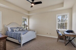 A bedroom with a bed, a desk, a chair, and a ceiling fan.