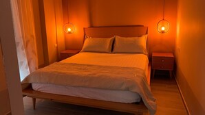 A bedroom with a wooden bed, two bedside tables, and two wall-mounted lamps.