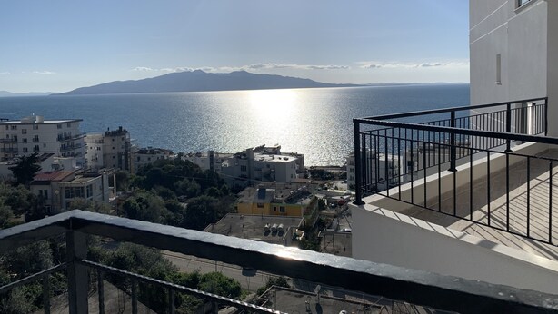 A balcony with a view of the sea and mountains.