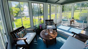 A covered patio with a round wooden table, two wooden chairs, and a bench. - NEW Dock with large platform.  Bring the boat!  Lakefront Farmhouse.   (Romulus)