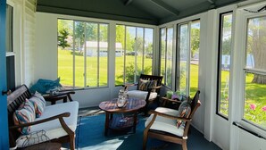 A sunroom with a wooden bench, a small table, and a chair. - NEW Dock with large platform.  Bring the boat!  Lakefront Farmhouse.   (Romulus)