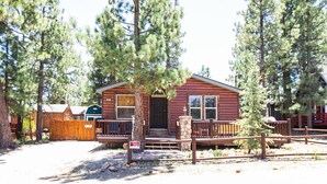 Un chalet avec une façade en bois, une véranda et une cheminée en pierre.