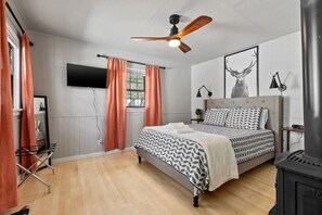 Une chambre à coucher avec un lit, un ventilateur de plafond, une cheminée et un téléviseur.