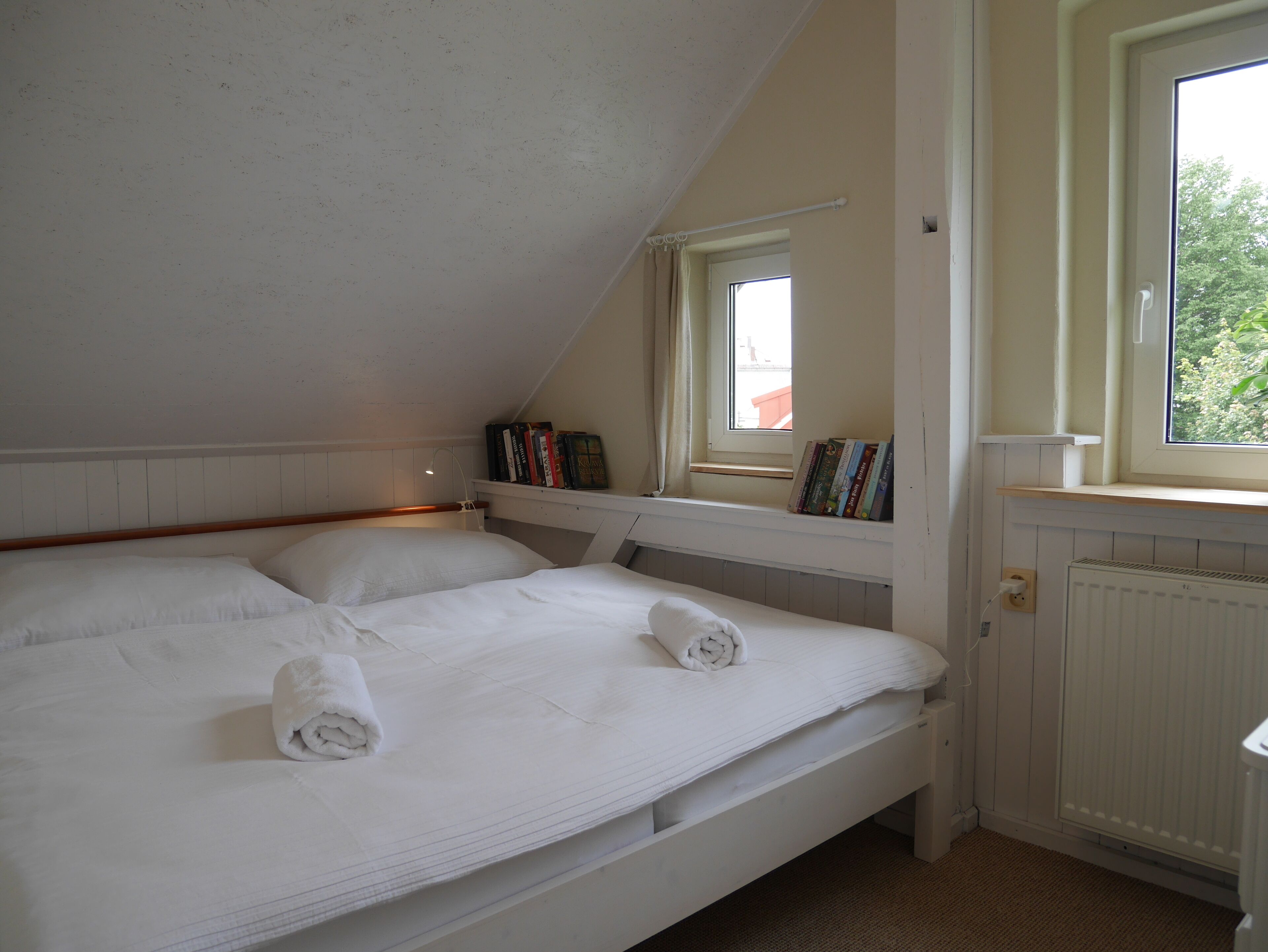 Une chambre avec un lit superposé, une fenêtre dont l’encadrement est garni de livres et un radiateur.