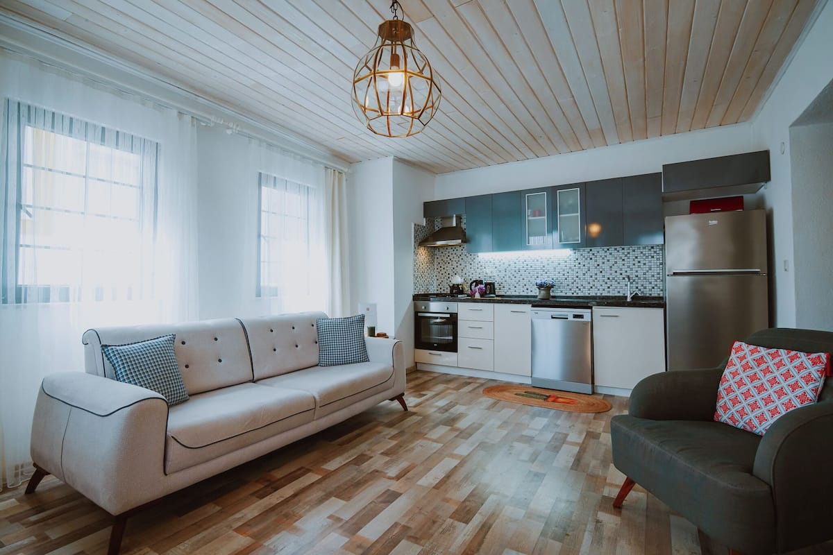 A modern kitchen with a wooden ceiling, white cabinets, and stainless steel appliances.