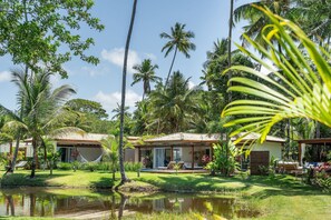Un resort tropical con dos villas, una piscina y abundante vegetación.