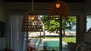 Habitación con vista a una piscina y una playa, que incluye una cama, una mesa con adornos y luces colgantes.