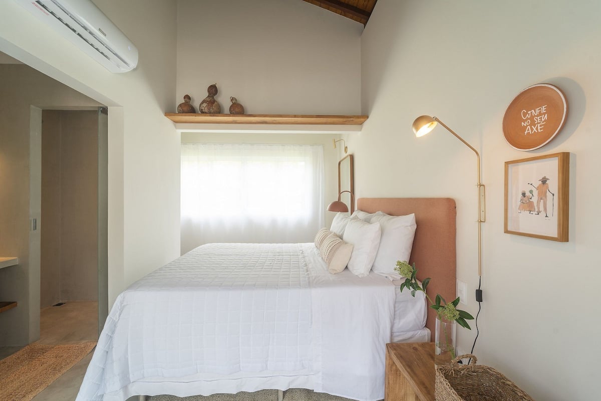 A bedroom with a bed, bedside lamp, wall decor, and a window.
