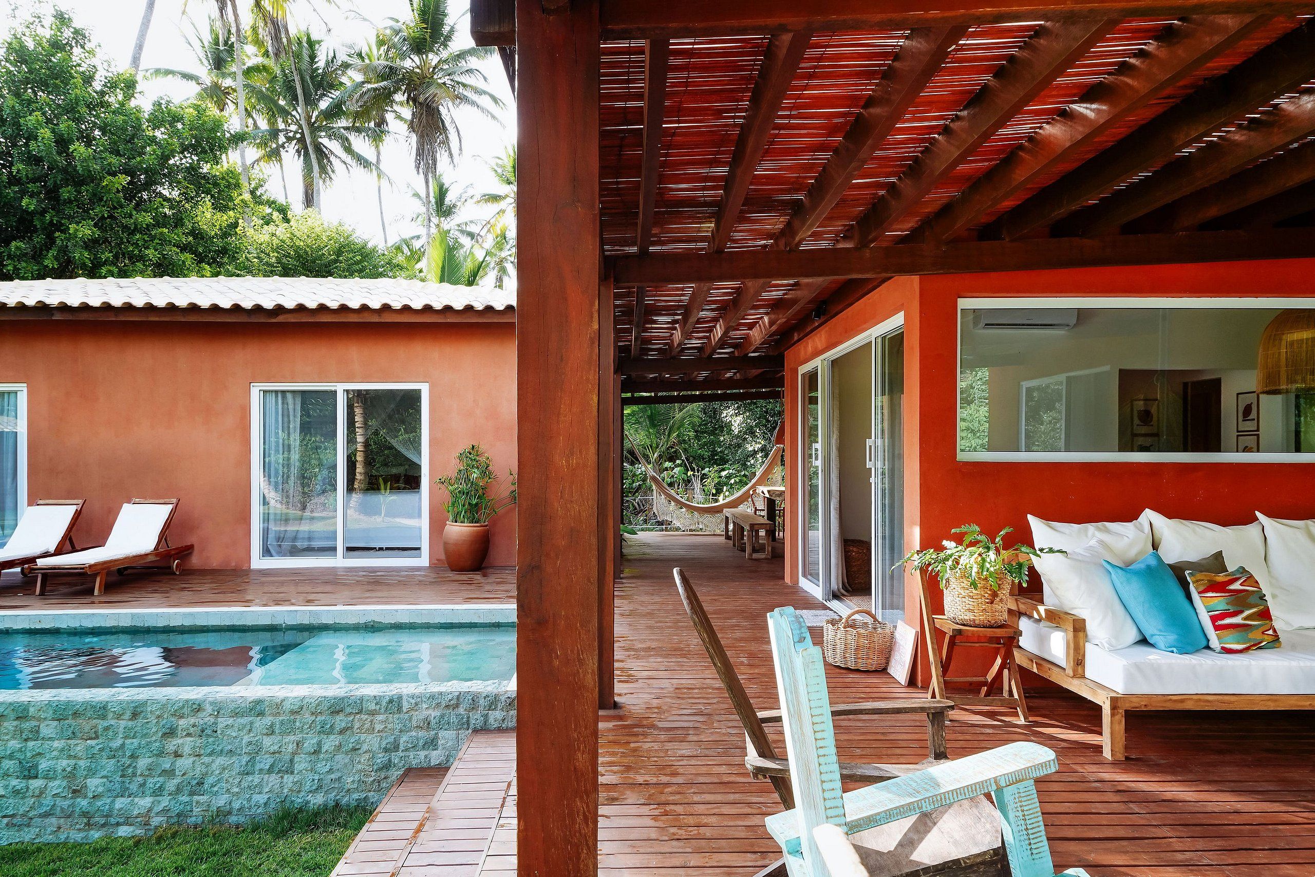 Eine Holzterrasse mit Pool, Liegestühlen und einer Hängematte.