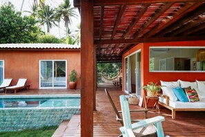 A wooden deck with a pool, lounge chairs, and a hammock. - Orixás Residence (Cairu)