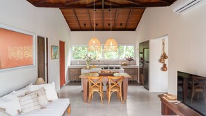 Una cocina moderna con comedor, techo de madera y ventanas amplias.