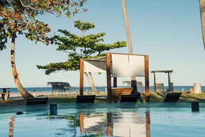 An outdoor pool area with lounge chairs and a wooden structure providing shade. - Orixás Residence (Cairu)