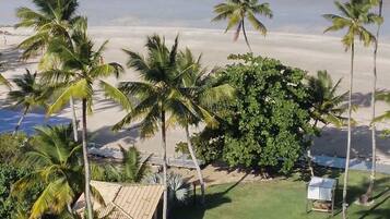 A beach house with a tiled roof, surrounded by palm trees and a view of the ocean.