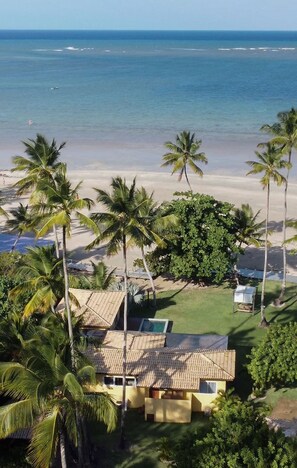 A beach house with a tiled roof, surrounded by palm trees and a view of the ocean. - Orixás Residence (Cairu)