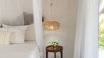 A bedroom with a canopy bed, a hanging light fixture, and a small table with a plant.