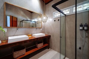 Casa de banho moderna com duas lavatórios, um espelho grande e cabine de duche em vidro.