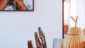 A framed photograph on a wall, a wicker basket on a table, and a wooden chair.