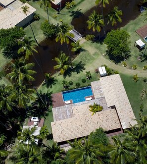 An aerial view of a resort with a swimming pool, palm trees, and a clear blue sky. - Orixás Residence (Cairu)