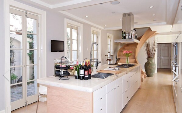 A spacious kitchen with a large island, a built-in oven, and a flat-screen TV mounted on the wall.