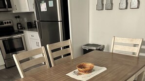 Ruokapöytä, jonka keskellä on punottu koriste-esine, ja pöydän ympärillä on puisia tuoleja, joissa on pehmustetut istuimet.