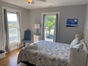 A bedroom with a bed, a chair, a nightstand, and a painting on the wall.